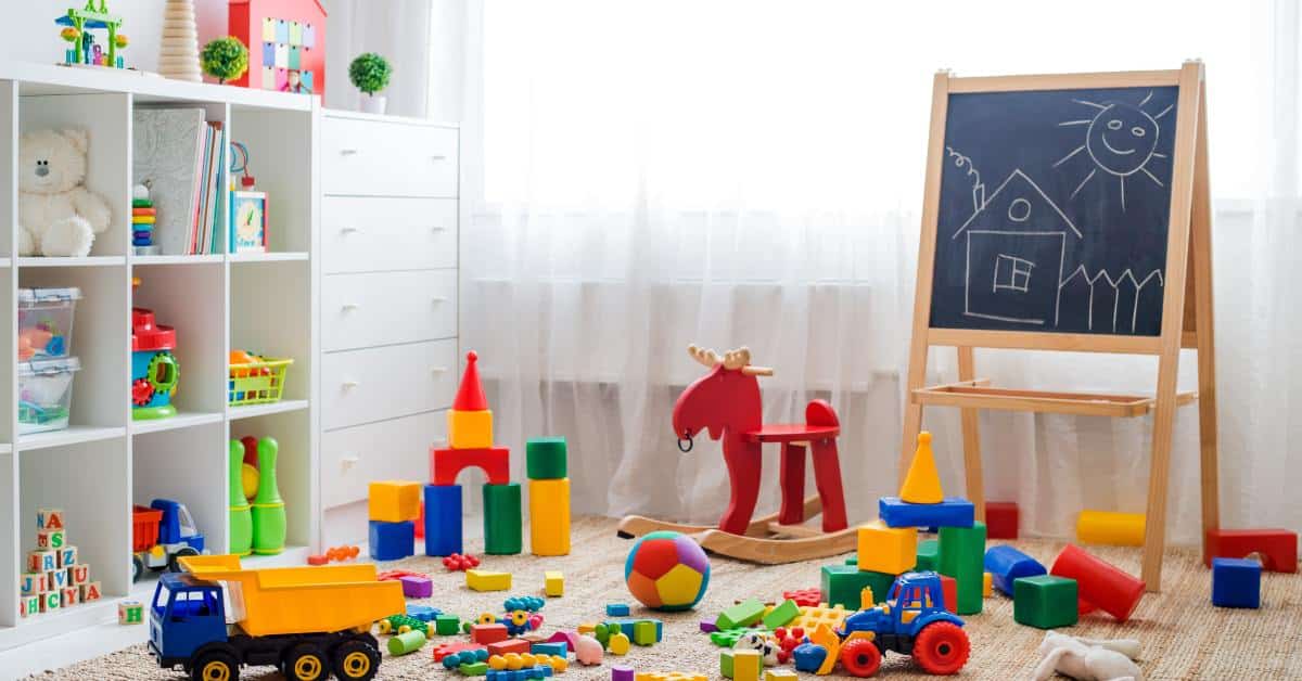 A room with colorful toys strewn about the ground. There is a window with the curtains drawn.