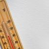 A thermometer is on a white surface. The mercury in the glass tube indicates the temperature is 30 degrees Celsius.