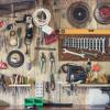 A wall is covered in tools. The wall is made out of wood and the tool are attached to wall hangings.