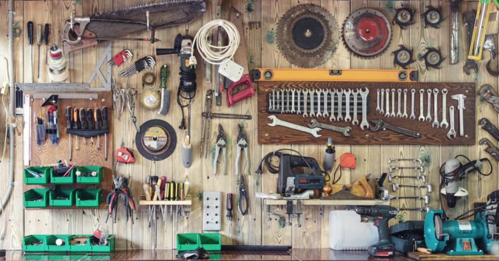A wall is covered in tools. The wall is made out of wood and the tool are attached to wall hangings.